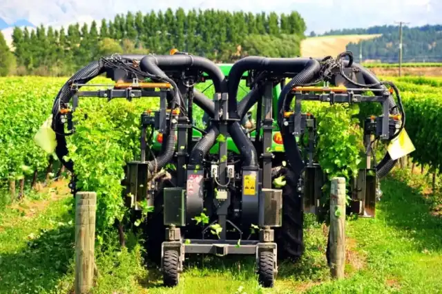 Connected agricultural equipment operating between rows of crops in a field.